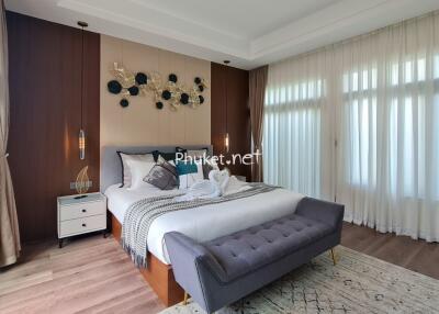 Modern bedroom with large windows, elegant decor, and a comfortable bed