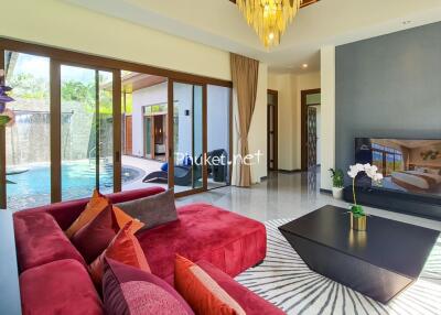 Spacious living room with red sofa, large TV, and pool view through glass doors