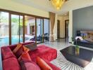 Spacious living room with red sofa, large TV, and pool view through glass doors