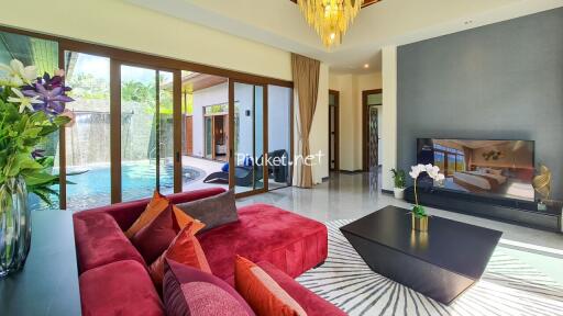 Spacious living room with red sofa, large TV, and pool view through glass doors