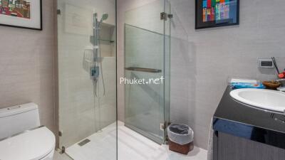 Modern bathroom with glass shower enclosure, white toilet, and wall-mounted sink