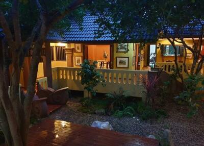 External view of a lit house at evening with a patio and garden