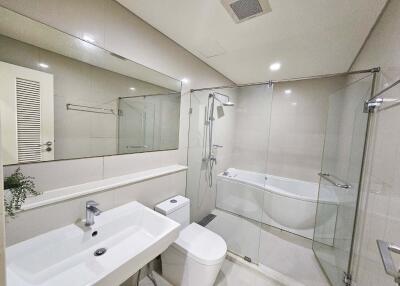 Modern bathroom with glass shower, bathtub, sink, and toilet