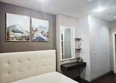 Modern bedroom with artwork, upholstered headboard, and vanity area