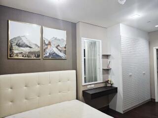 Modern bedroom with artwork, upholstered headboard, and vanity area