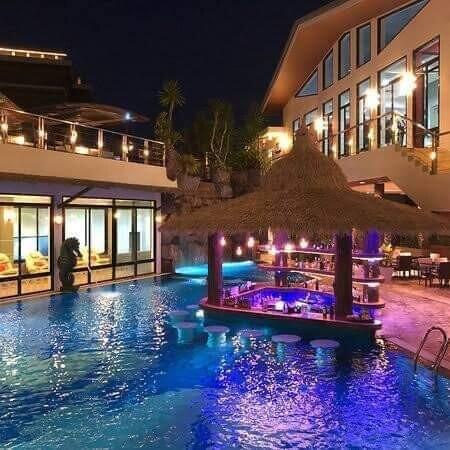 Luxurious outdoor pool area at night with bar seating