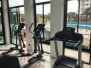 Home gym with cardio equipment and large windows overlooking an outdoor area