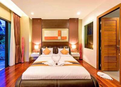 Modern bedroom with wooden flooring, a large bed, balcony, and ambient lighting