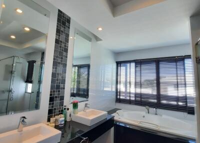 Modern bathroom with double sinks, large bathtub, and big windows