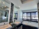 Modern bathroom with double sinks, large bathtub, and big windows