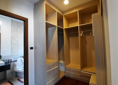Walk-in closet with built-in shelving and drawers, view into adjacent bathroom