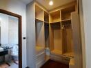 Walk-in closet with built-in shelving and drawers, view into adjacent bathroom