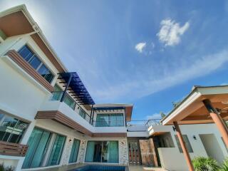 Modern multi-story house with large windows and outdoor pool against a clear blue sky