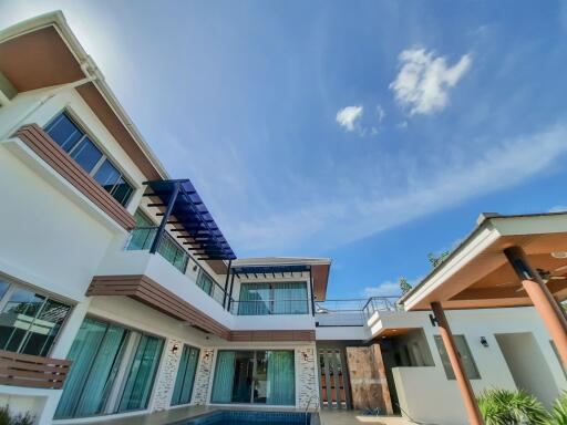 Modern multi-story house with large windows and outdoor pool against a clear blue sky