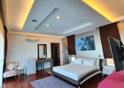 Spacious bedroom with modern ceiling lighting, hardwood floor, and cozy furniture