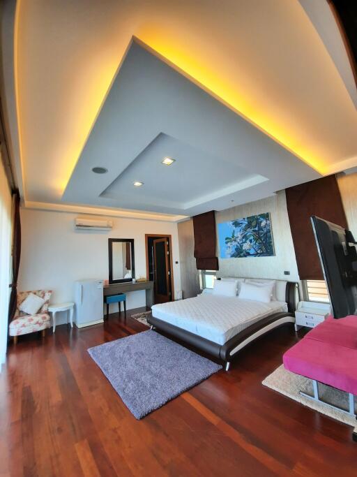 Spacious bedroom with modern ceiling lighting, hardwood floor, and cozy furniture