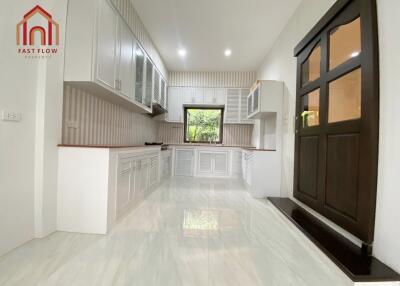 Modern kitchen with white cabinetry, large window, and wooden door