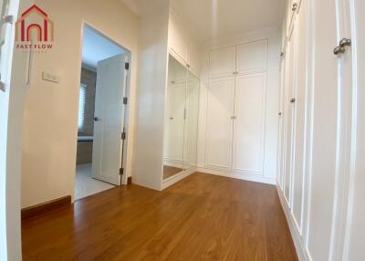 Spacious closet with wooden flooring and white cabinetry