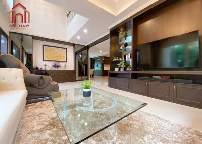 Spacious modern living room with a glass coffee table, plush rug, and built-in entertainment unit