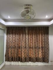 Living room with ceiling fan and patterned curtains