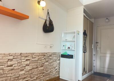 Entrance hallway with stone accent wall, wall-mounted light, and storage shelf