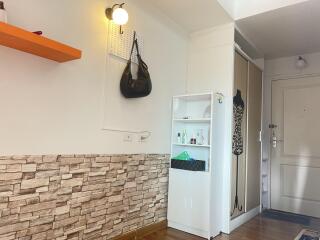 Entrance hallway with stone accent wall, wall-mounted light, and storage shelf