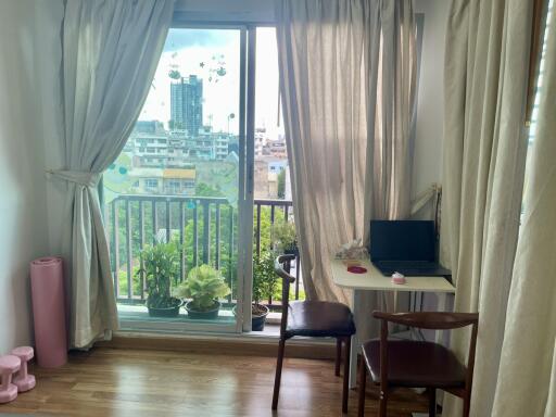 Well-lit living area with a small office setup and balcony view