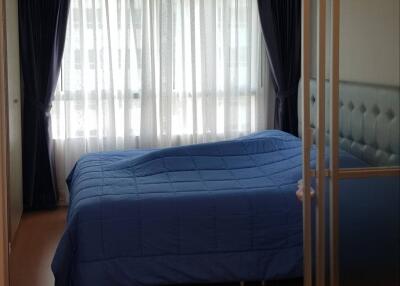 Bedroom with blue bedding and large window with curtains