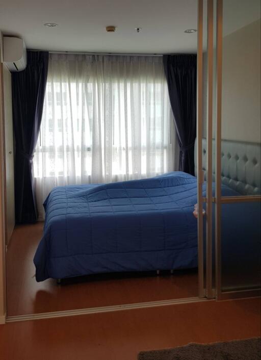 Bedroom with blue bedding and large window with curtains