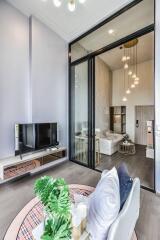 Modern living room with TV and access to bedroom through sliding glass doors