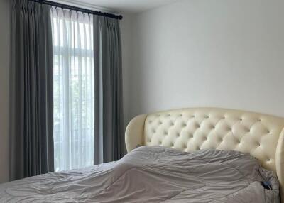 Bedroom with upholstered bed and window with curtains