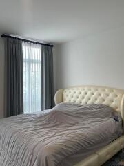 Bedroom with upholstered bed and window with curtains