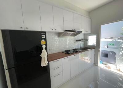 Modern kitchen with white cabinets and black refrigerator