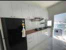 Modern kitchen with white cabinets and black refrigerator