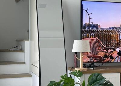 Living room with a staircase, floor mirror, TV, lamp, and houseplant