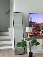 Living room with a staircase, floor mirror, TV, lamp, and houseplant