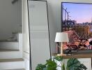 Living room with a staircase, floor mirror, TV, lamp, and houseplant