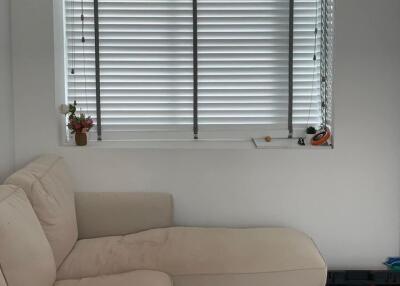 Living room with a beige sectional sofa and window with blinds