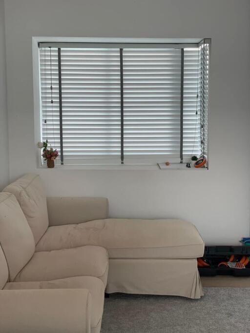 Living room with a beige sectional sofa and window with blinds