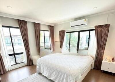 Spacious and bright bedroom with hardwood floors, large windows, and an air conditioner.