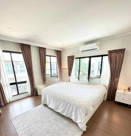 Spacious and bright bedroom with hardwood floors, large windows, and an air conditioner.