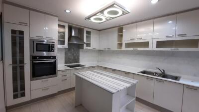 Modern kitchen with white cabinets, island, and built-in appliances