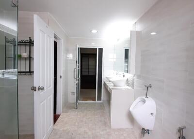 Modern bathroom with glass shower, double sinks, and urinal