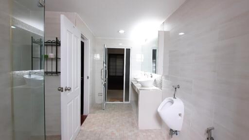 Modern bathroom with glass shower, double sinks, and urinal