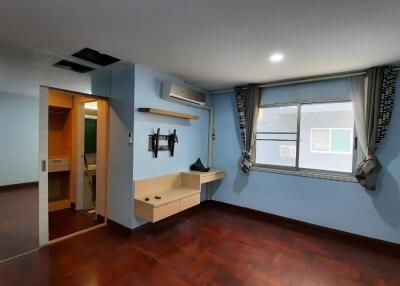 Spacious bedroom with large window, wall-mounted TV, air conditioning, and wooden floor