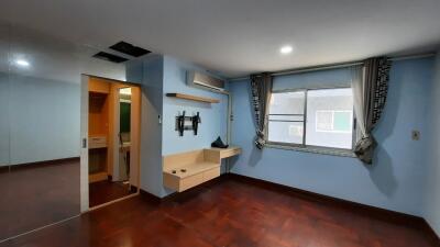 Spacious bedroom with large window, wall-mounted TV, air conditioning, and wooden floor