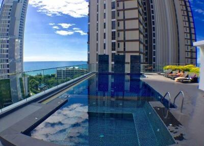 Rooftop swimming pool with a view of the ocean and nearby buildings