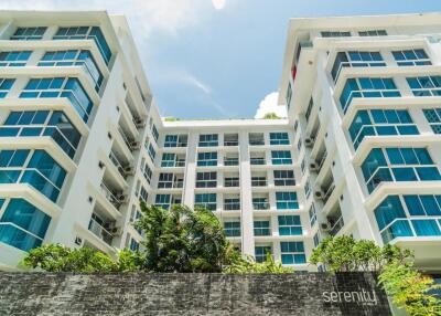 Modern apartment building exterior with large windows and greenery