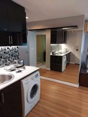 Modern kitchen with black cabinets, washing machine, and stainless steel sink