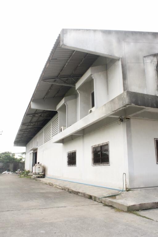 Exterior view of a large industrial building with multiple windows and a covered loading area